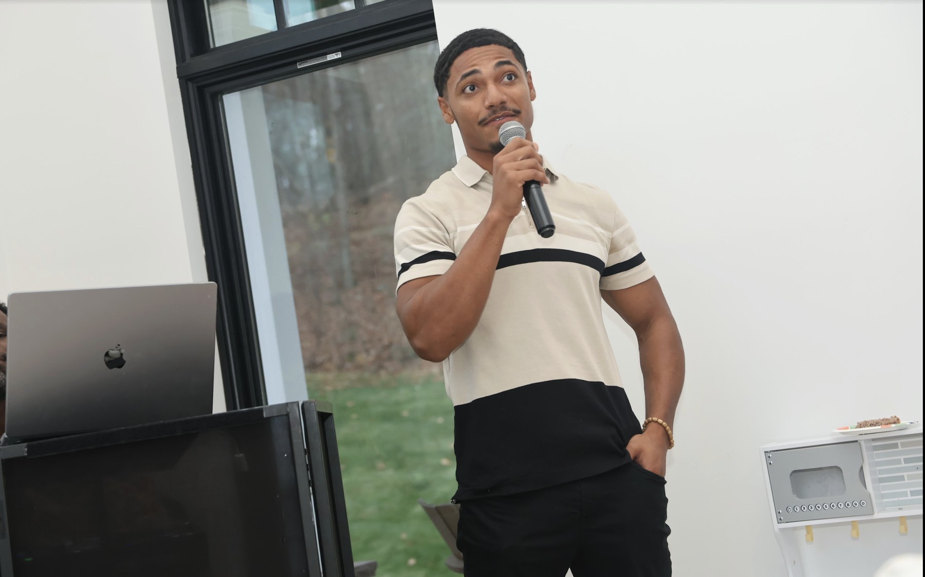 Elijah Naylor Jr. speaking with a microphone in an educational setting